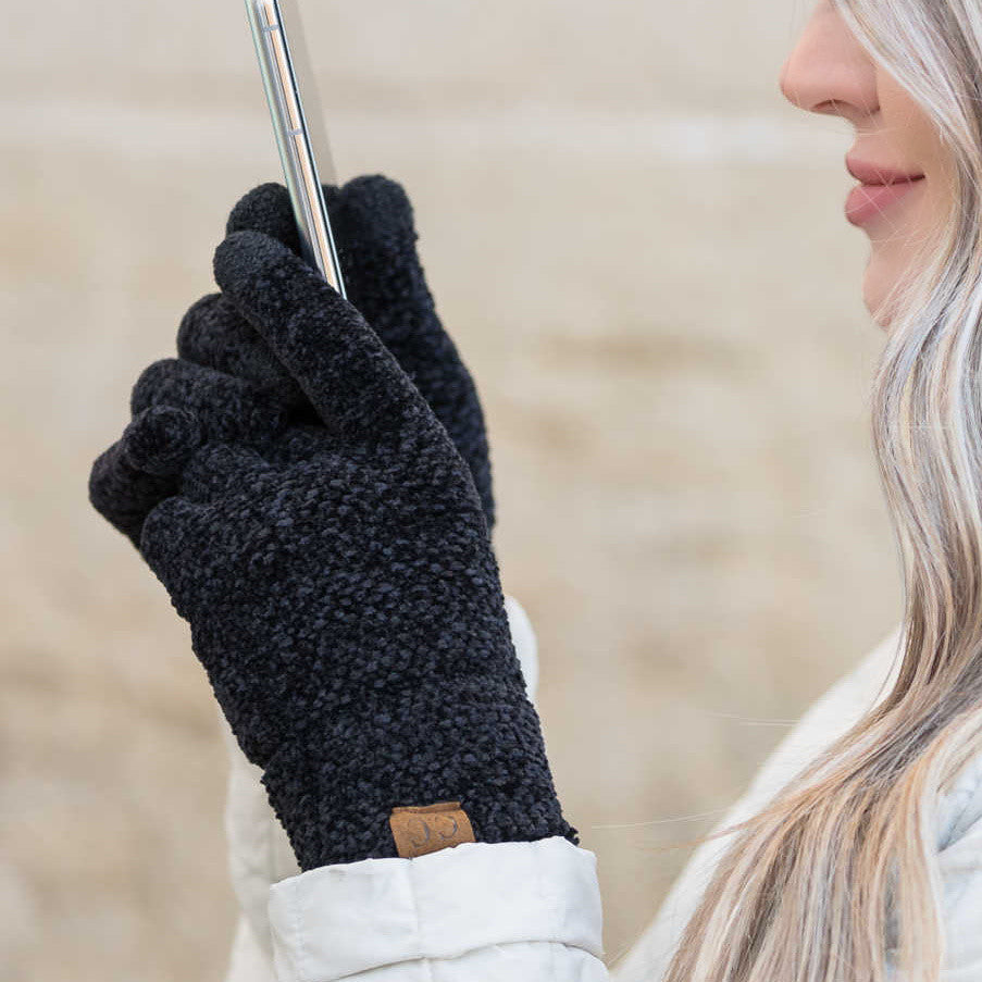 Black textured gloves worn while holding a phone.