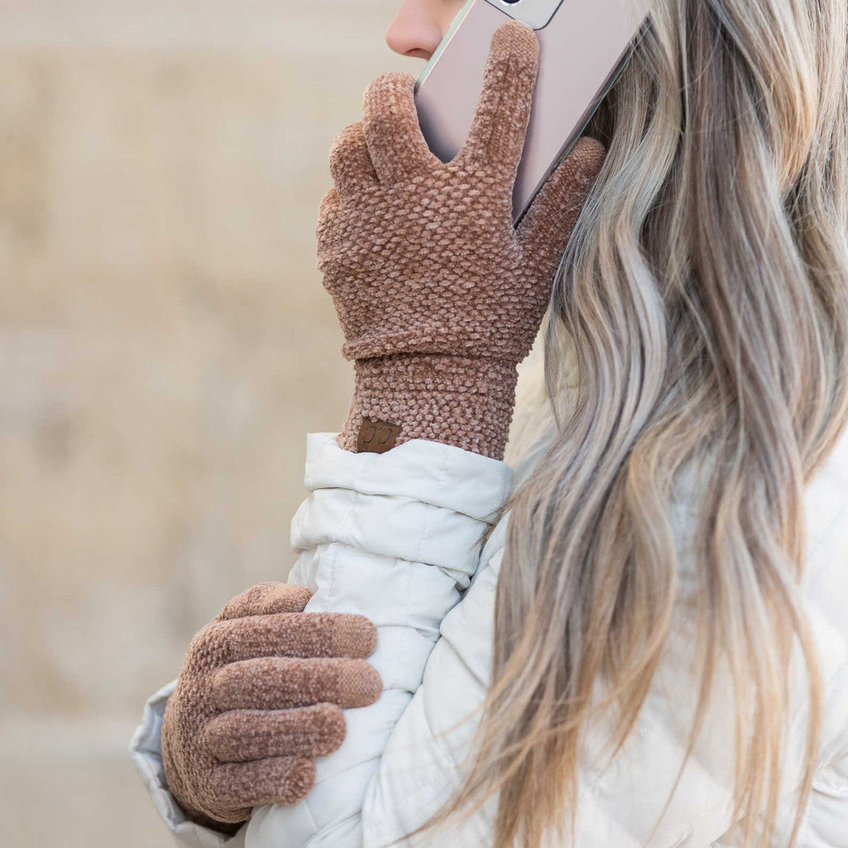 Brown textured gloves worn while holding a phone.