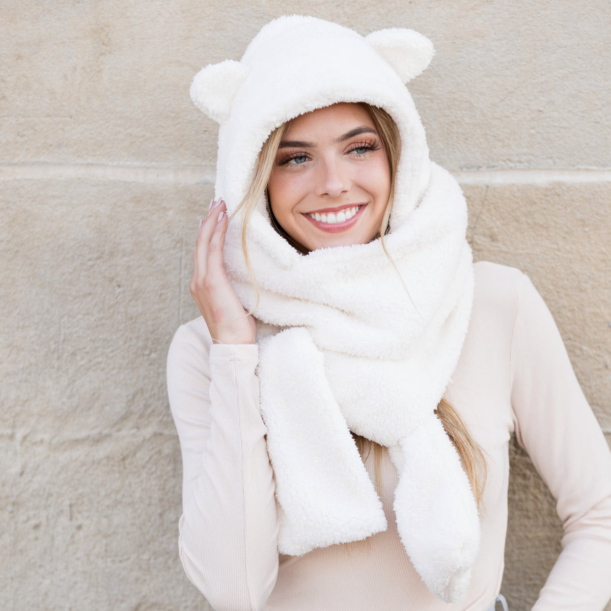 Cream plush hooded scarf with bear-ear details worn on a model.