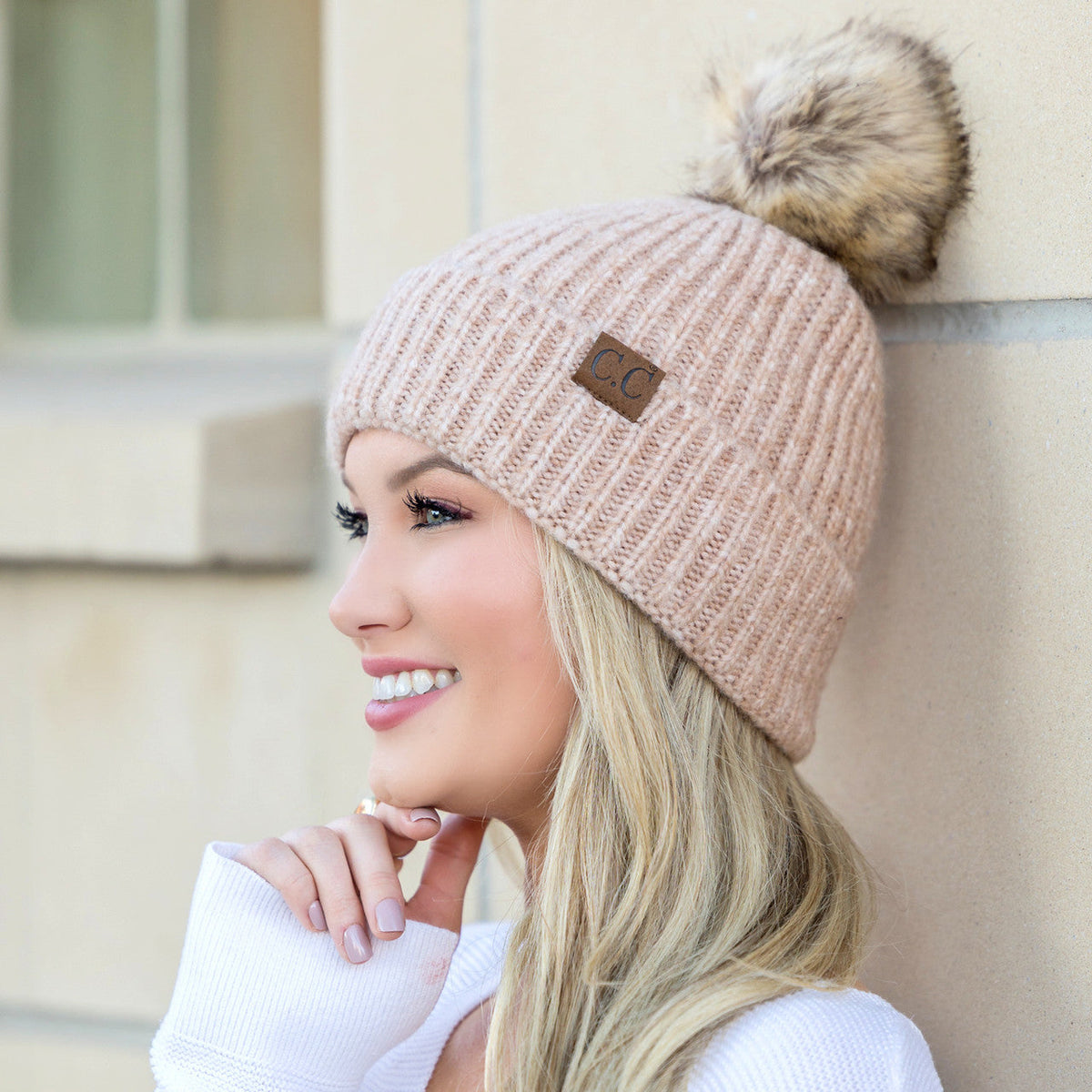 Blush marled knit beanie with a brown pom worn on a model.