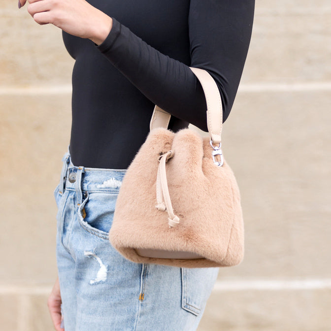 Camel plush bag carried at the elbow.