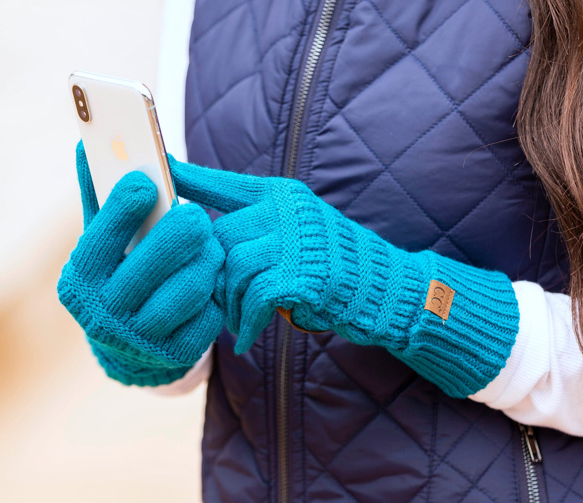Teal cable-knit gloves worn while holding a phone.