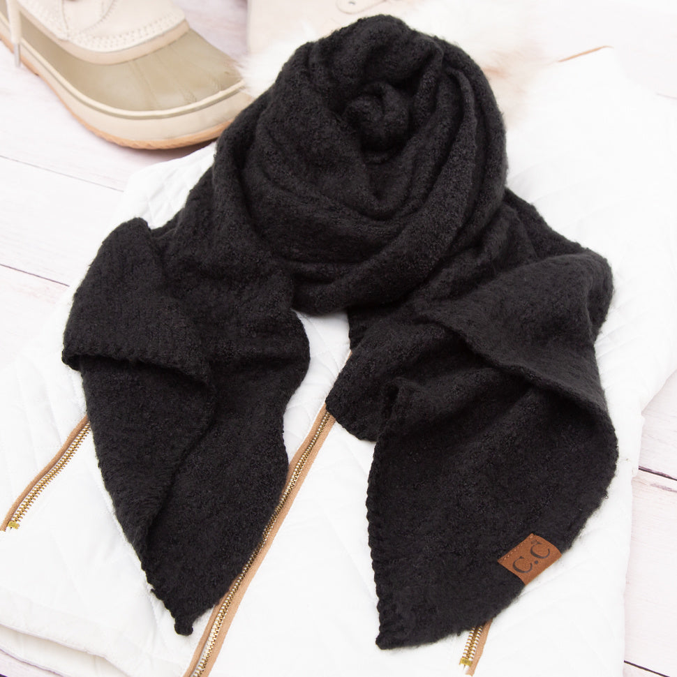 Black scarf arranged beside a beige hat.