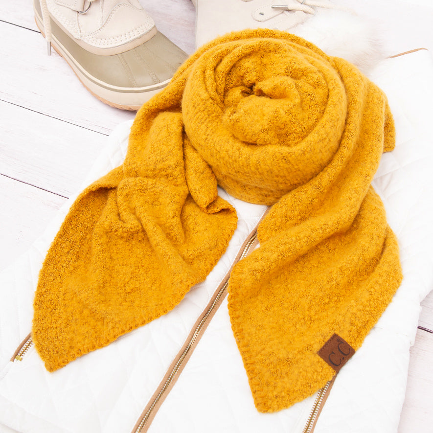 Mustard yellow scarf arranged beside a beige hat.
