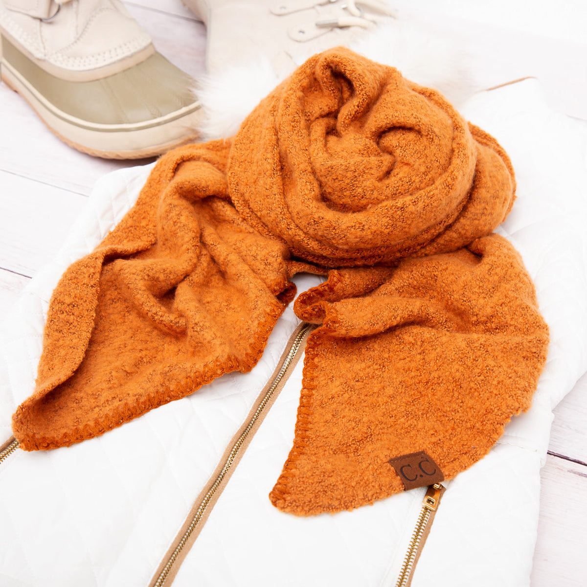 Rust orange scarf arranged beside a beige hat.
