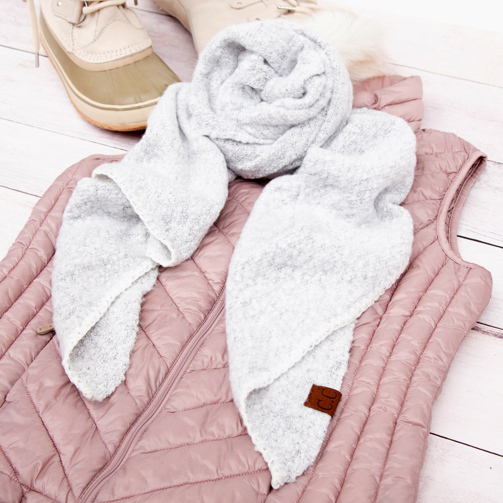 White scarf arranged over pink knit clothing.