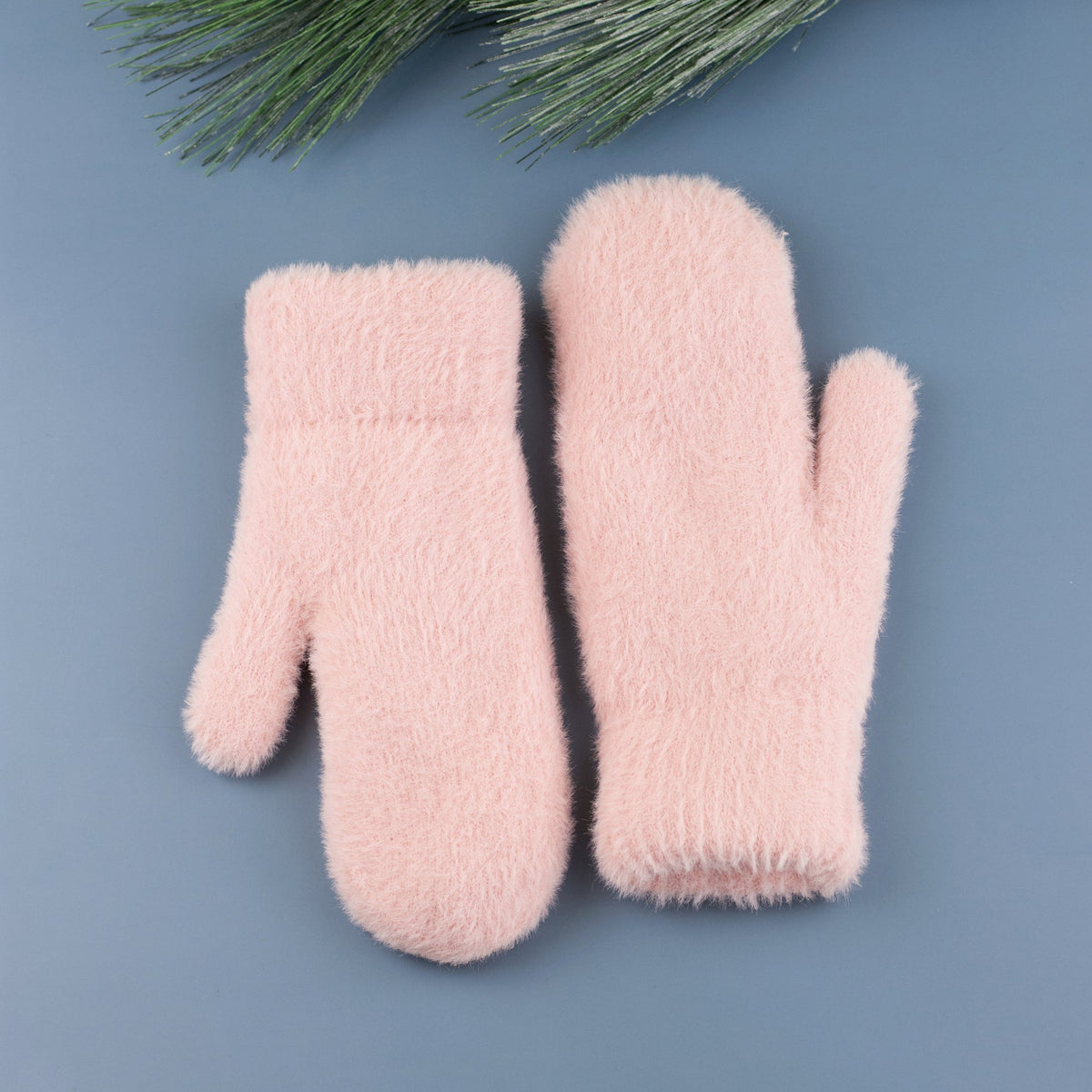 Blush pink plush mittens displayed on a blue background.