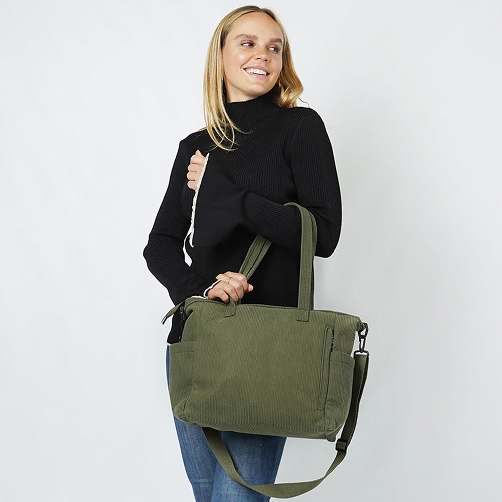 Woman holding olive green corduroy multi-pocket tote bag with crossbody strap