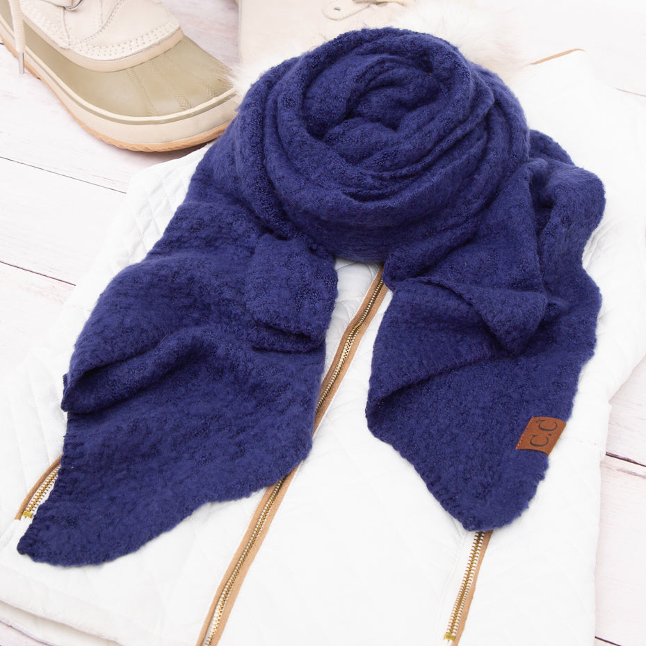 Deep blue scarf arranged beside a beige hat.