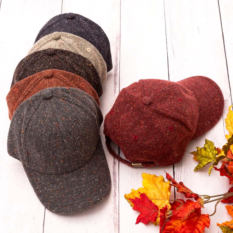 Tweed-style baseball caps arranged beside autumn-leaf styling props.