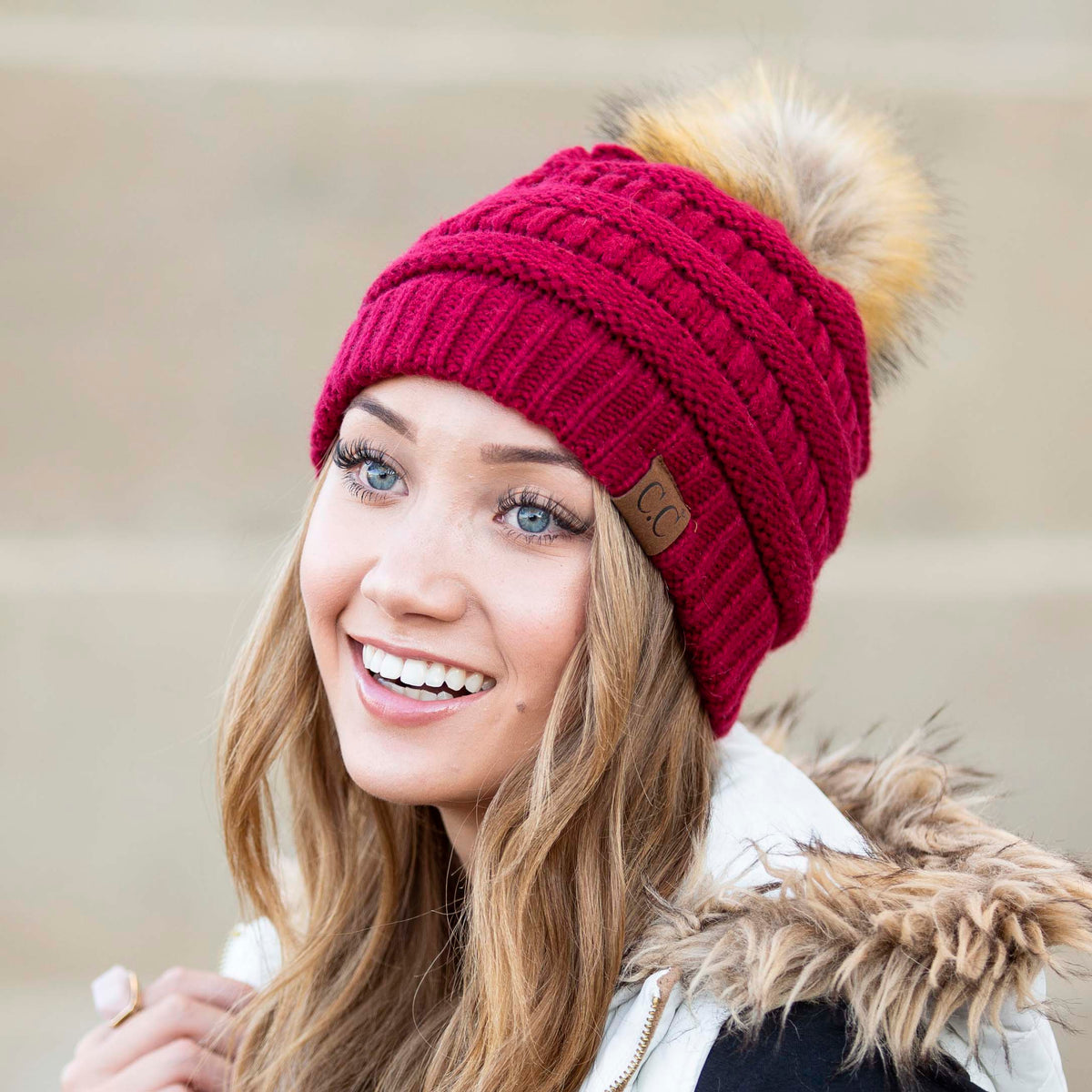 Burgundy textured knit beanie with a light brown pom worn on a model.