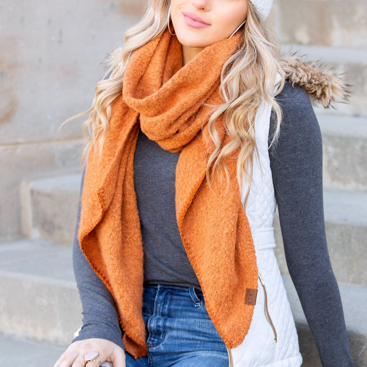 Rust orange draped scarf worn with a dark sweater.