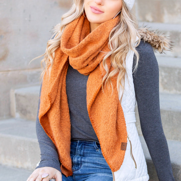 Rust orange draped scarf worn with a dark sweater.