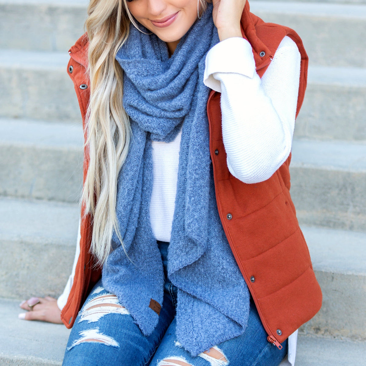 Denim blue draped scarf worn with a rust-colored vest.