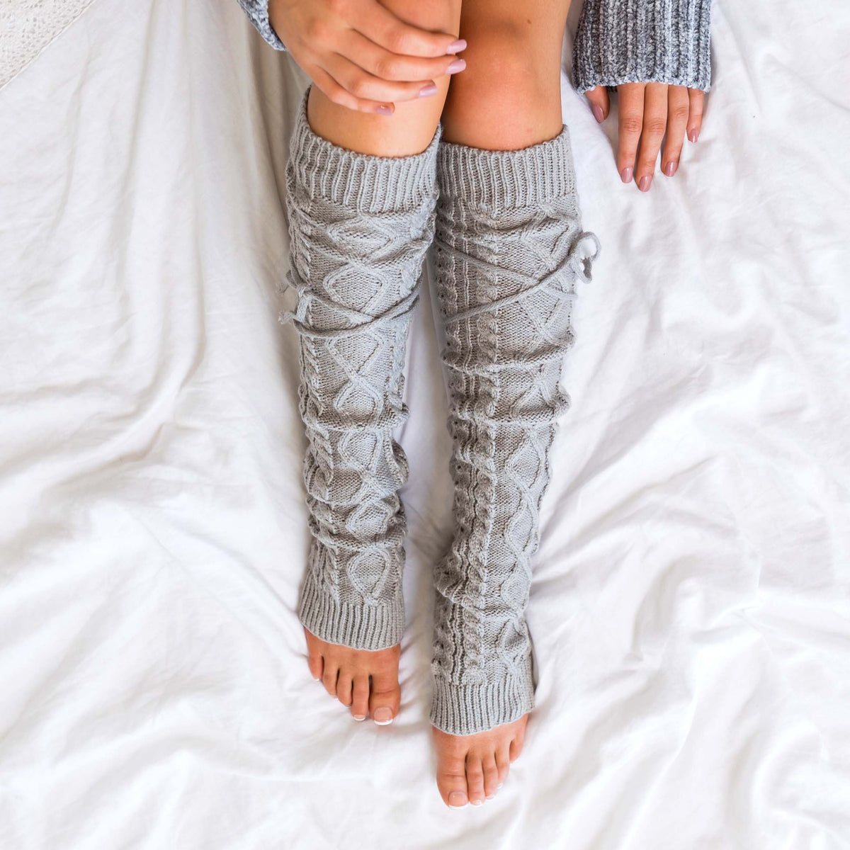 Grey cable-knit leg warmers shown from above.