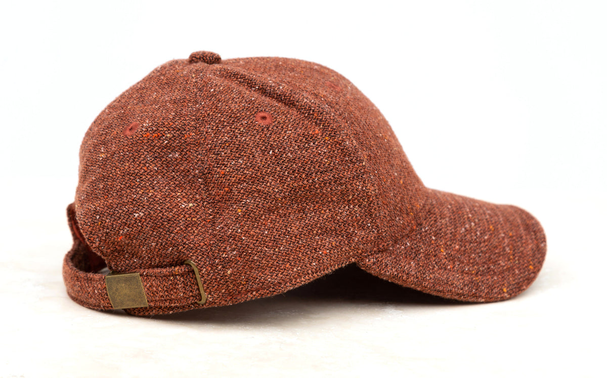 Rust-colored tweed-style baseball cap shown from the side on a white background.