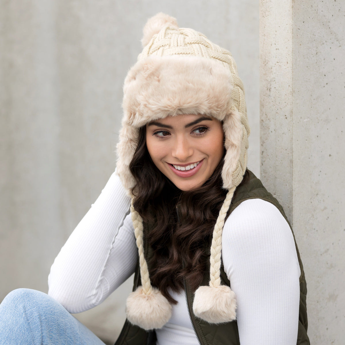Ivory cable-knit pom trapper hat shown from the front.