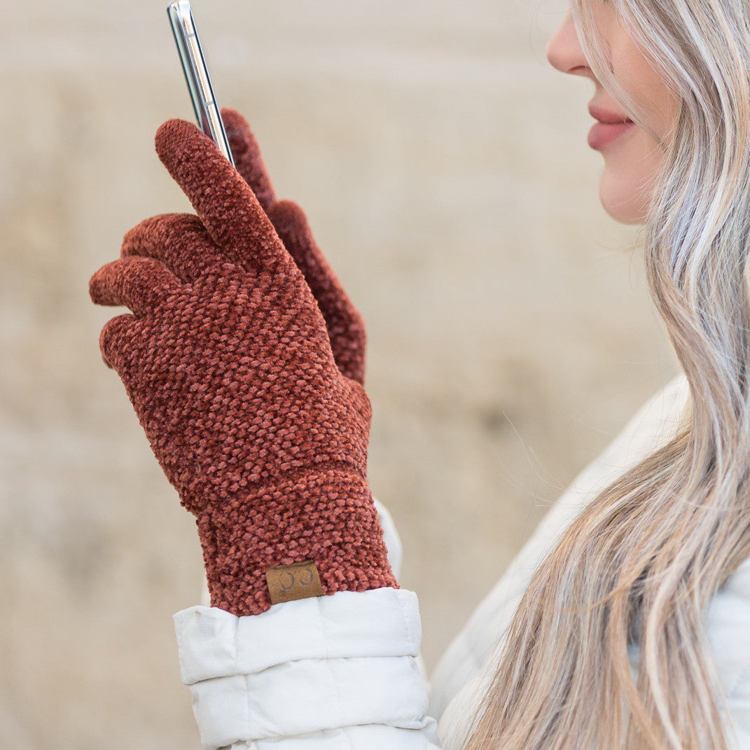 Rust-colored textured gloves worn while holding a phone.
