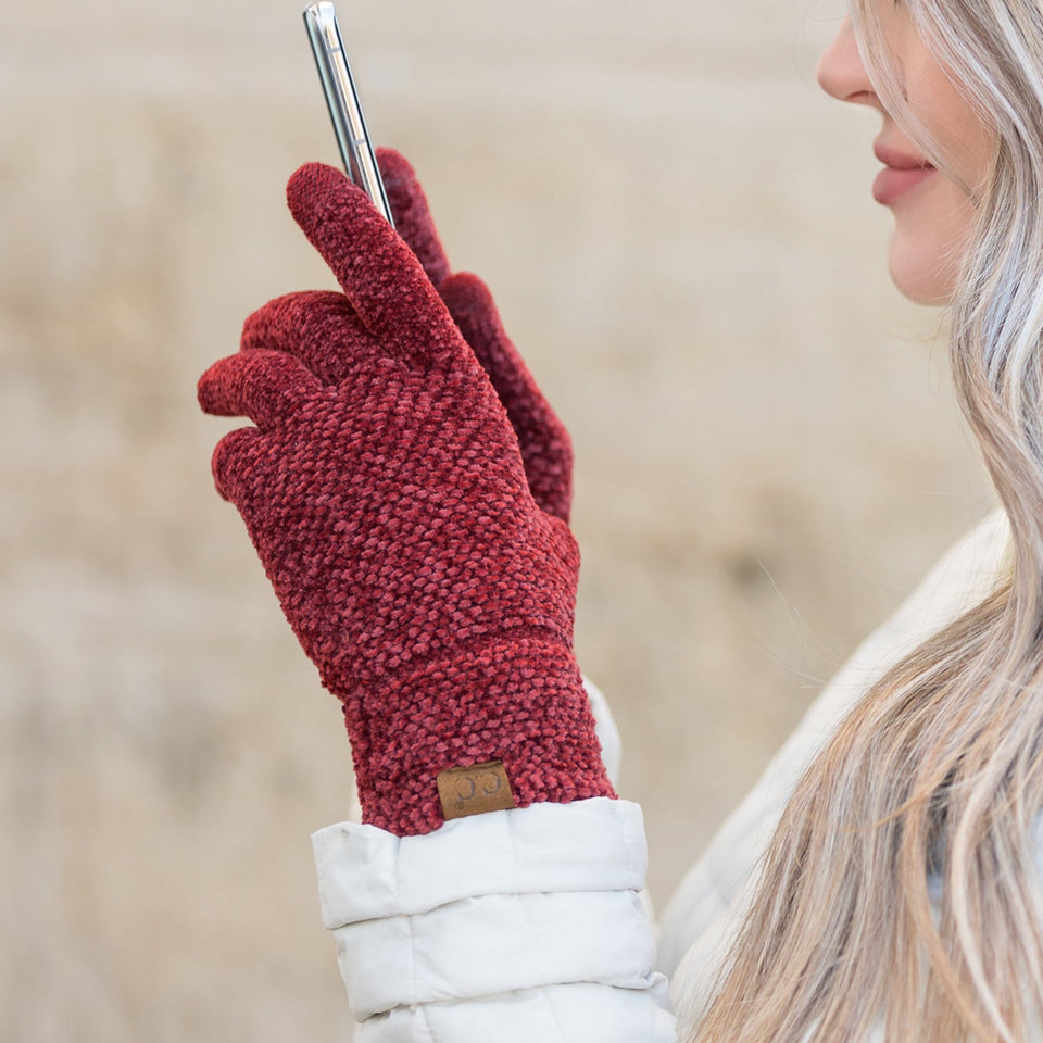 Burgundy textured gloves worn while holding a phone.