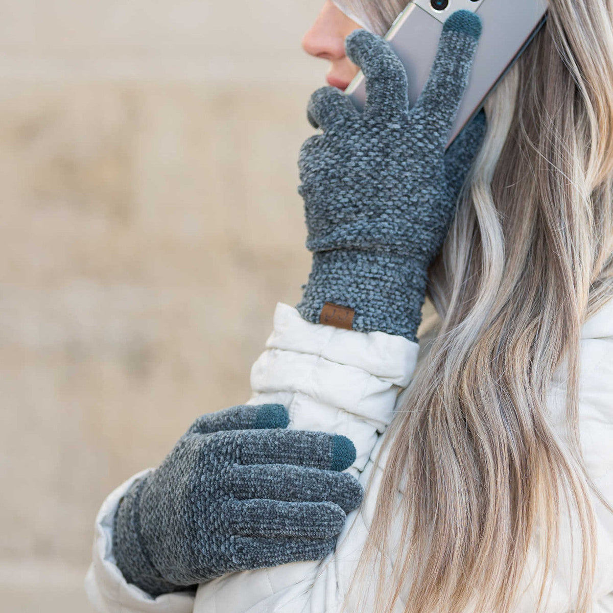 Blue-grey textured gloves worn while holding a phone.