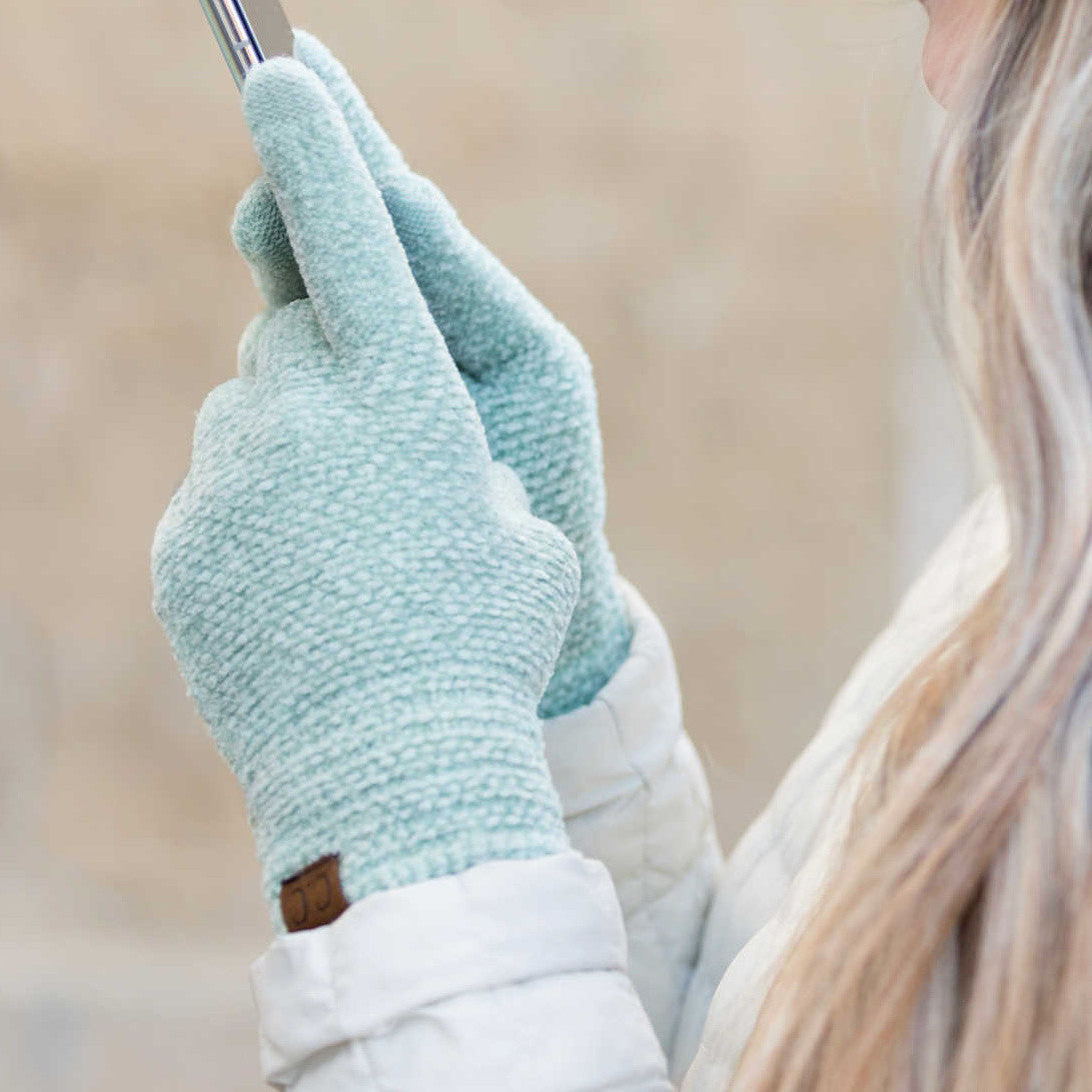 Mint-colored textured gloves worn while holding a phone.