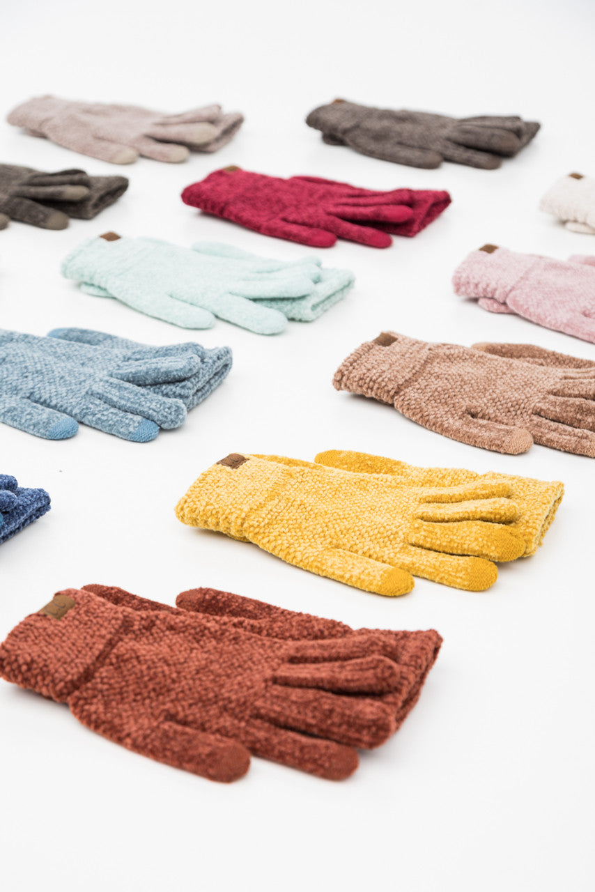 Textured gloves in several colors arranged on a light surface.