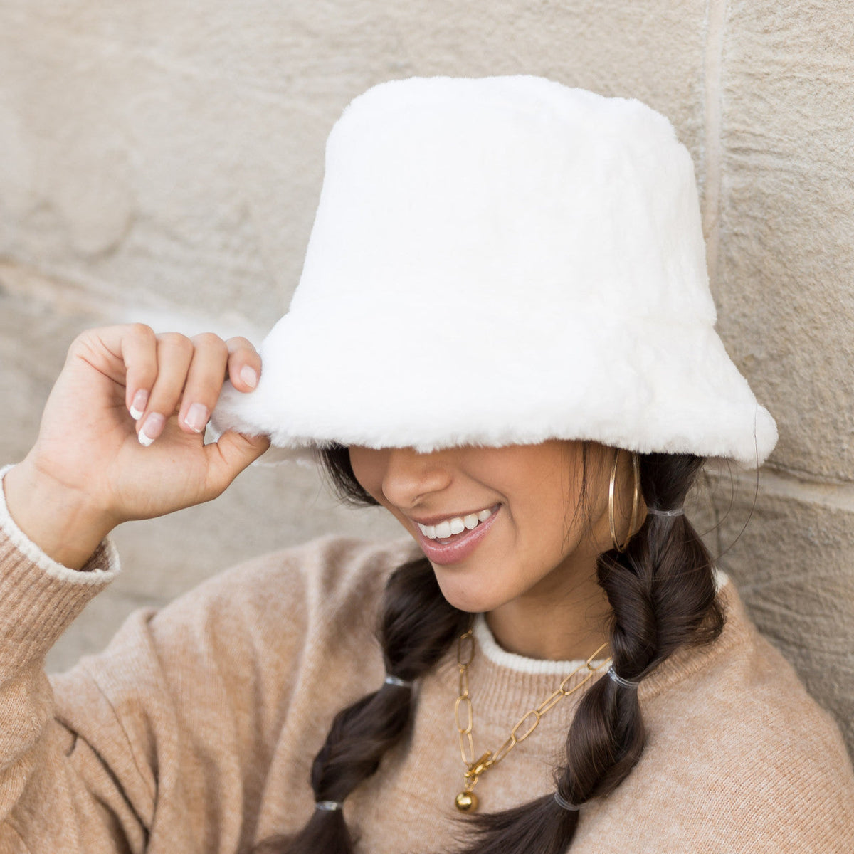 White plush bucket hat worn low over the forehead.