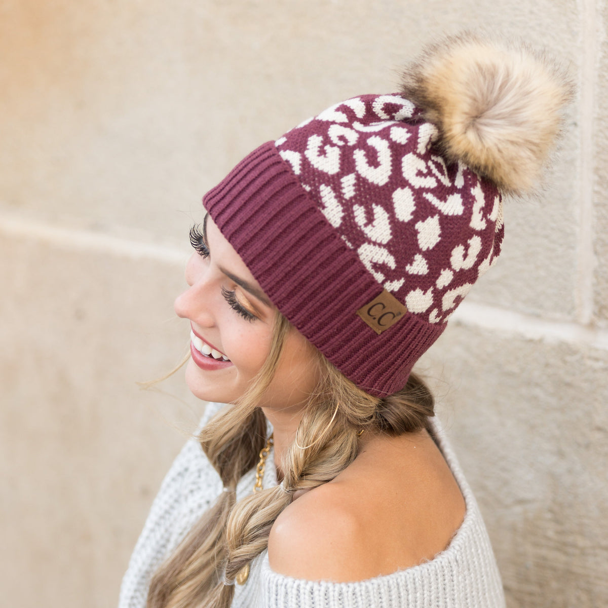 Burgundy leopard-pattern beanie with a brown pom worn on a model.