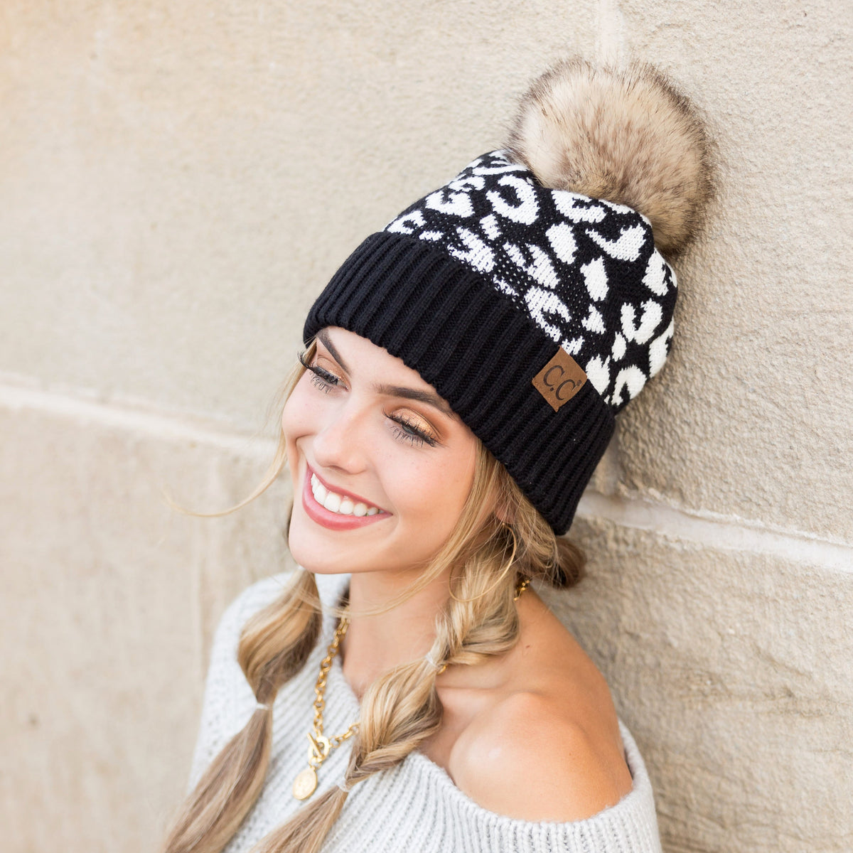 Black and white leopard-pattern pom beanie worn on a model.