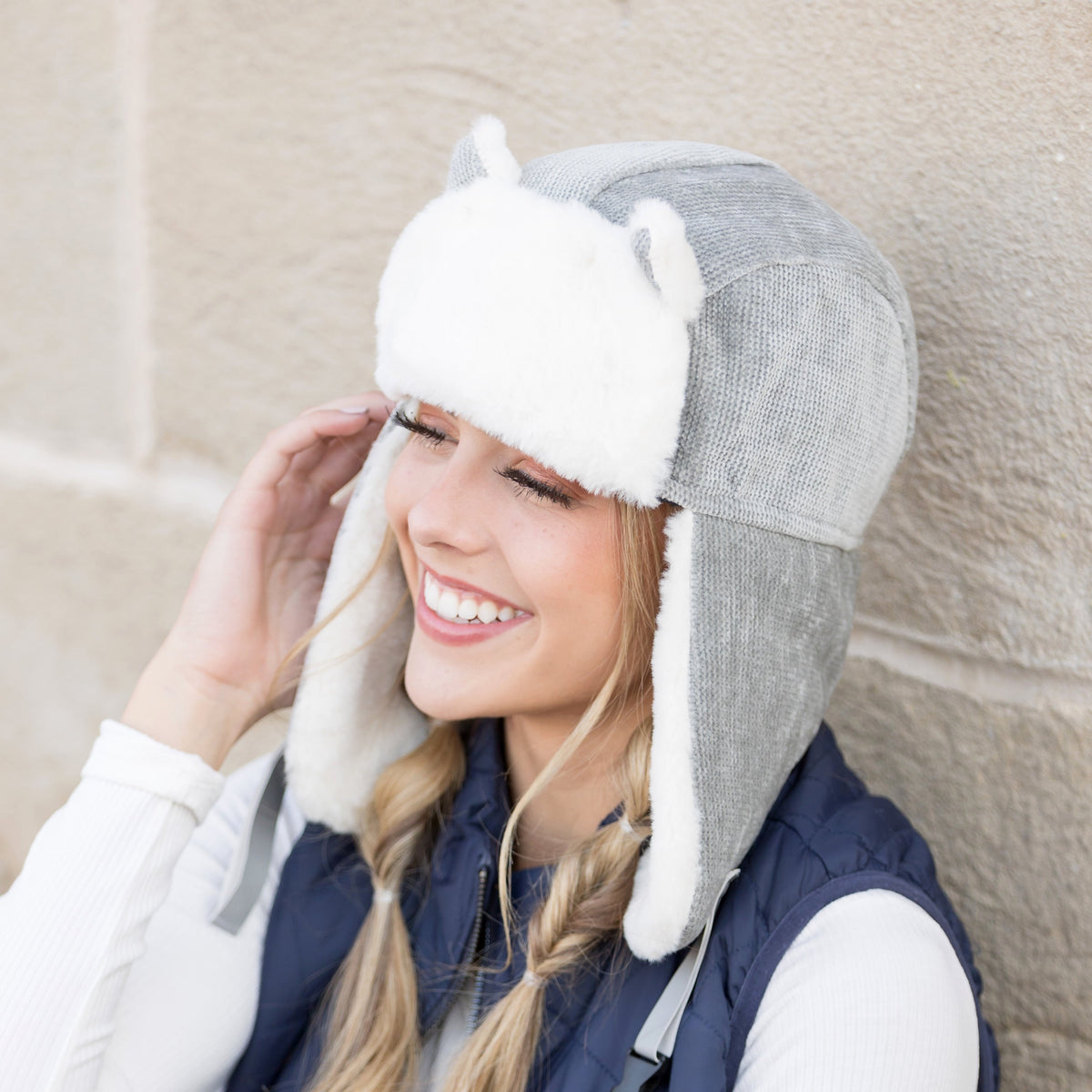 Grey kitten-ear trapper hat with white trim worn on a model.