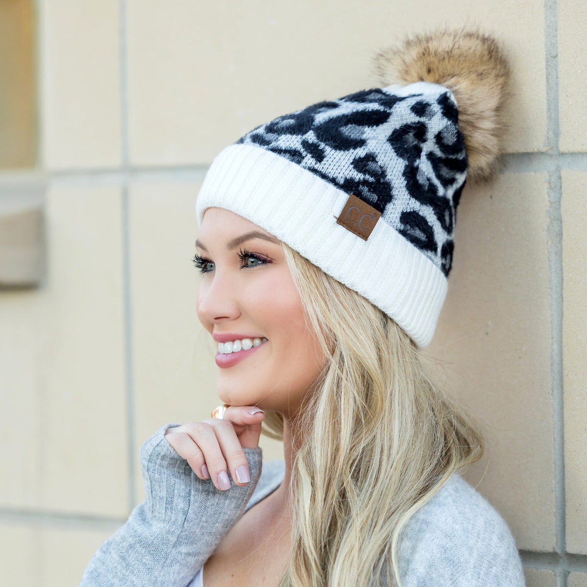 White and black leopard-print pom beanie worn on a model.