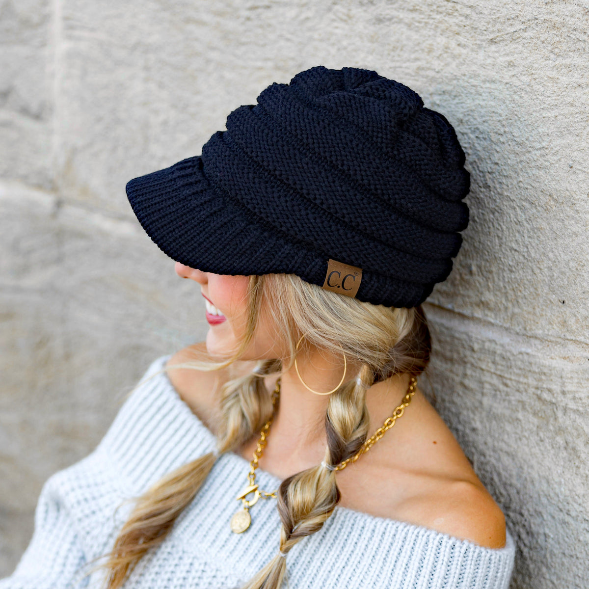 Dark knit brimmed cap shown from the side on a model.
