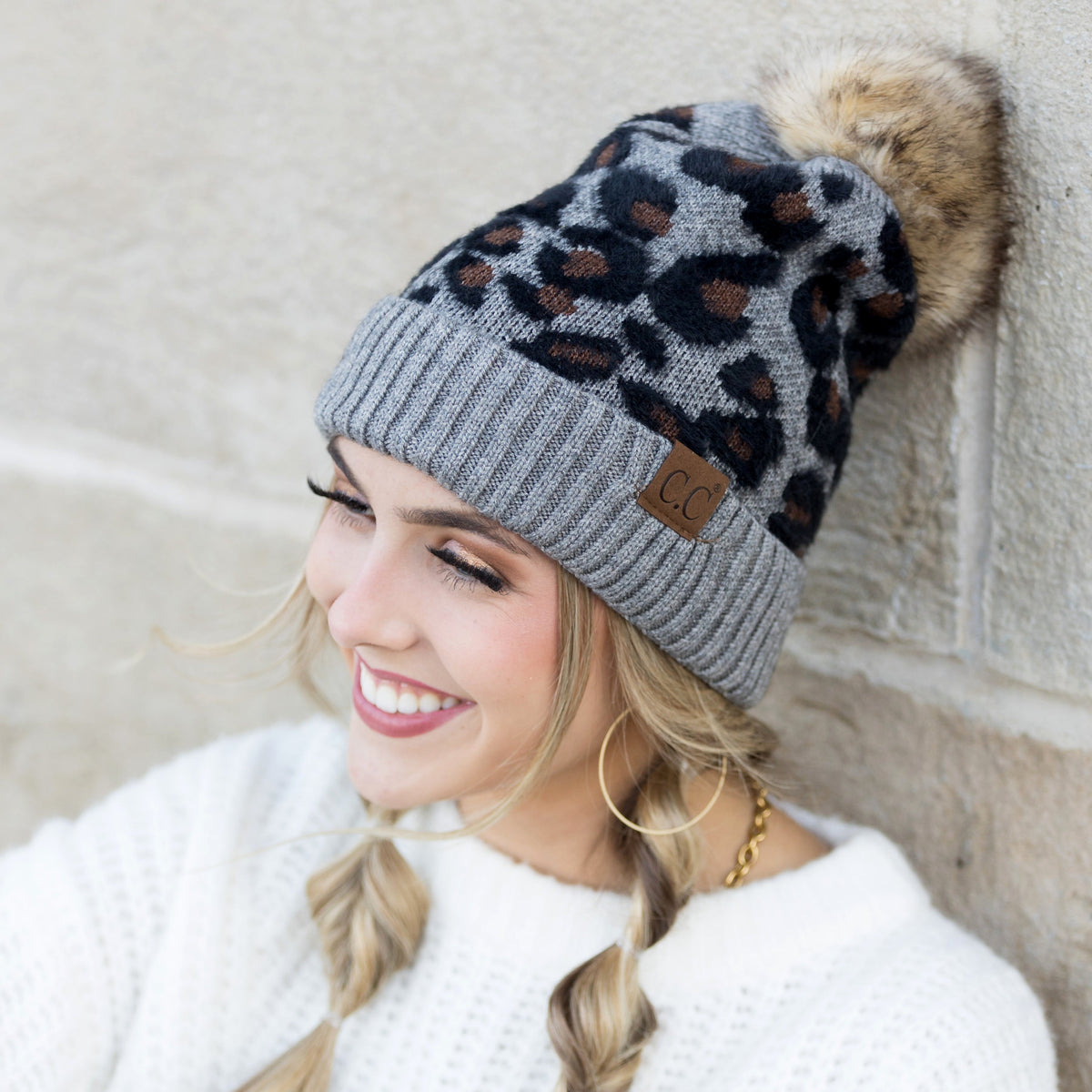 Grey and black leopard-print pom beanie worn on a model.