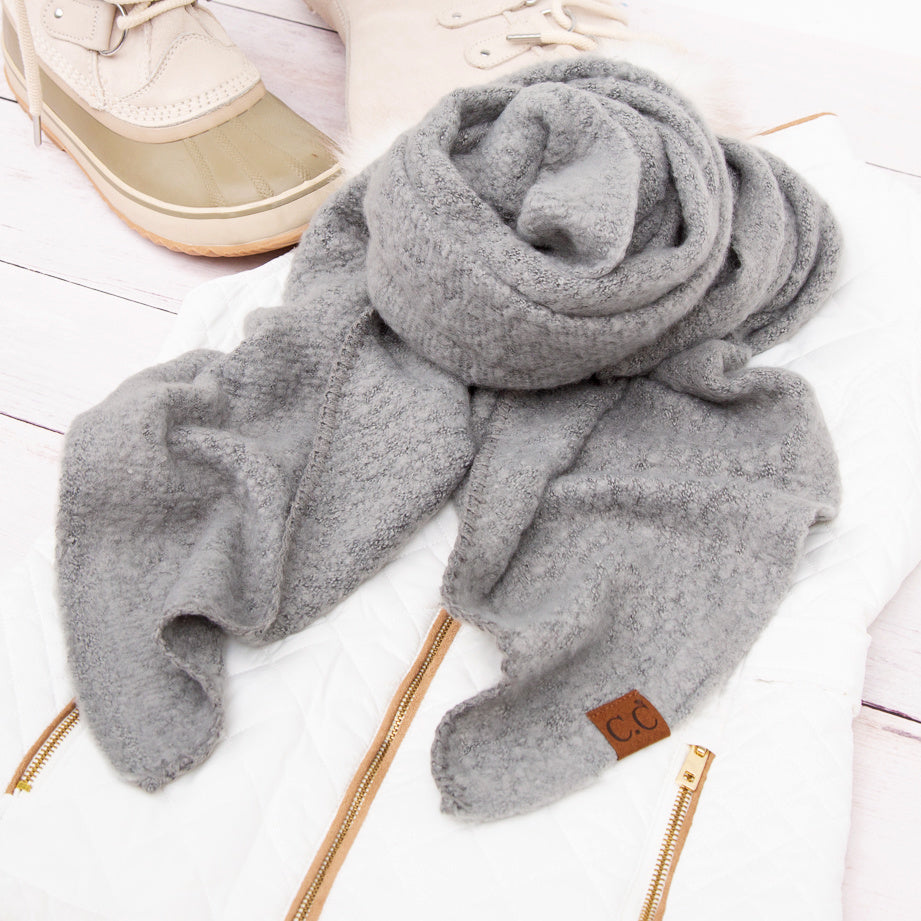 Grey scarf arranged beside a beige hat.