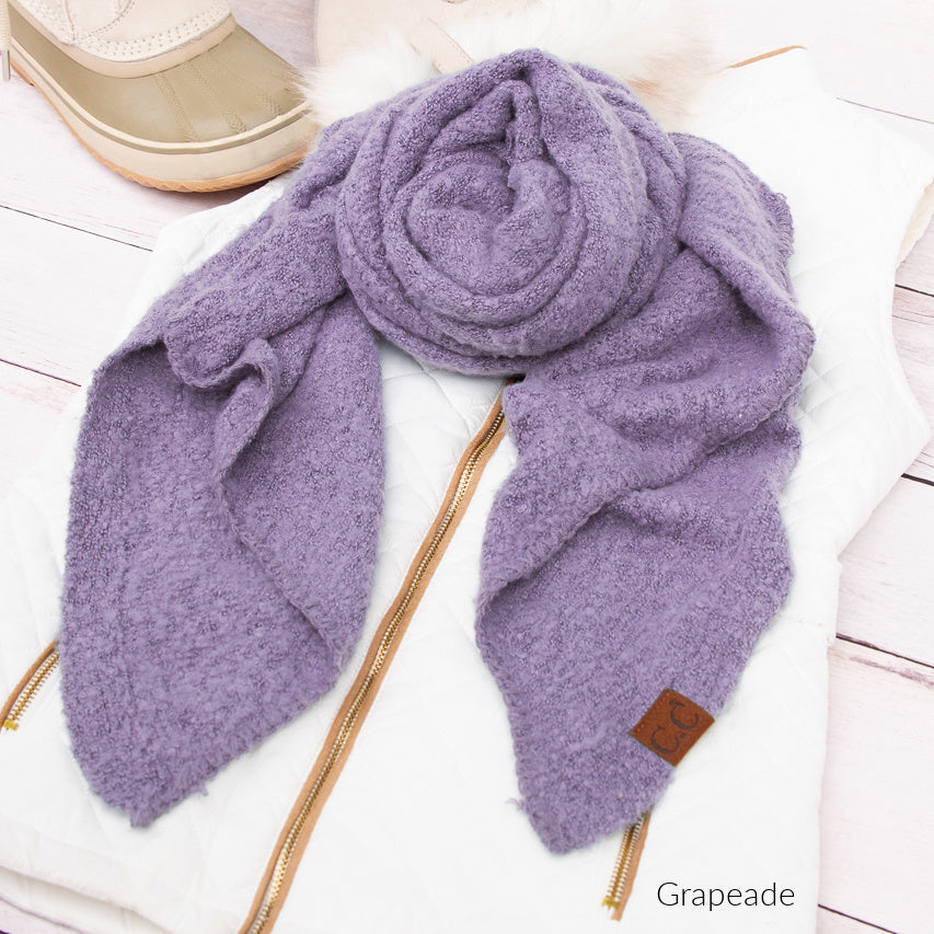 Purple scarf arranged beside a beige hat.