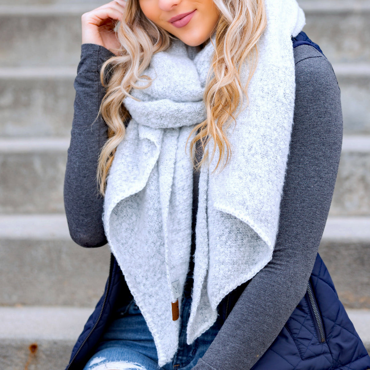Light grey draped scarf worn with a dark sweater.
