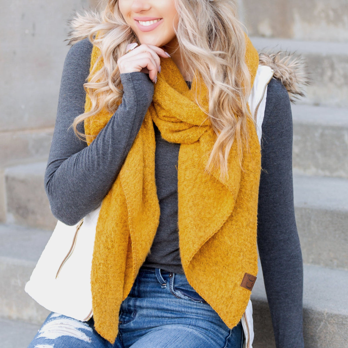 Mustard yellow draped scarf worn with a dark sweater.