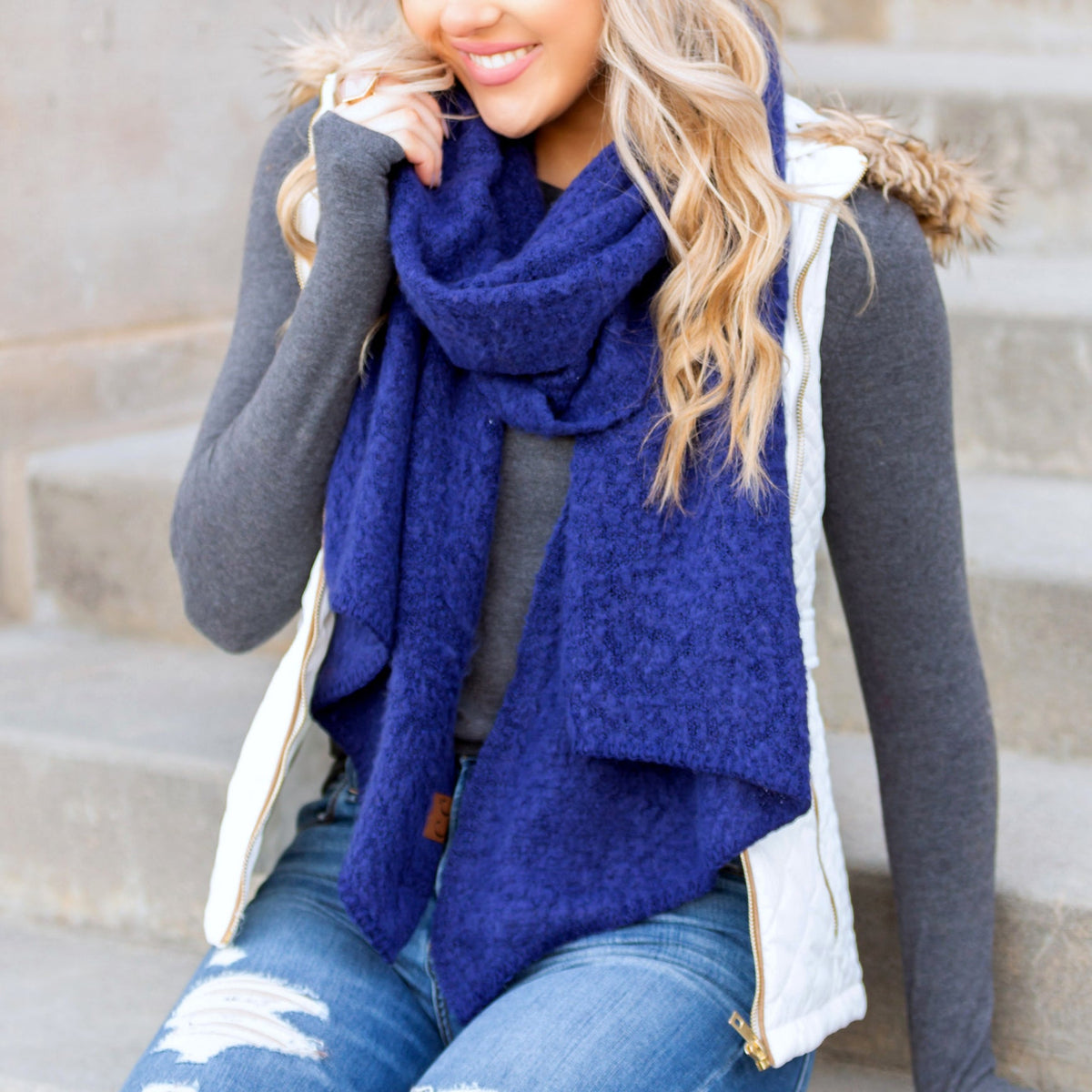 Deep blue draped scarf worn with a dark sweater.