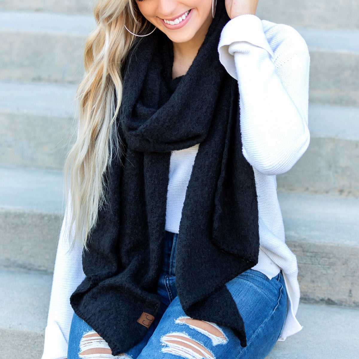Black draped scarf worn over a light top.