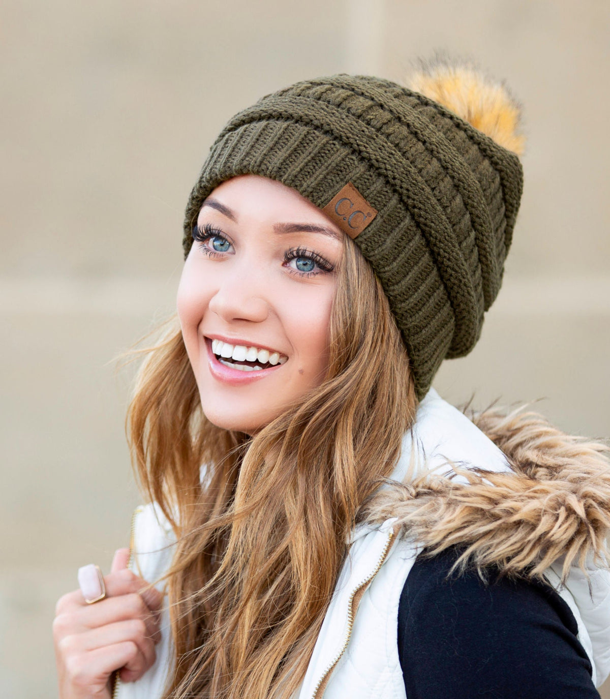 Olive green textured knit pom beanie worn on a model.