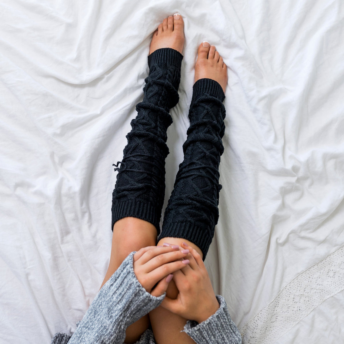 Black cable-knit leg warmers shown from above.