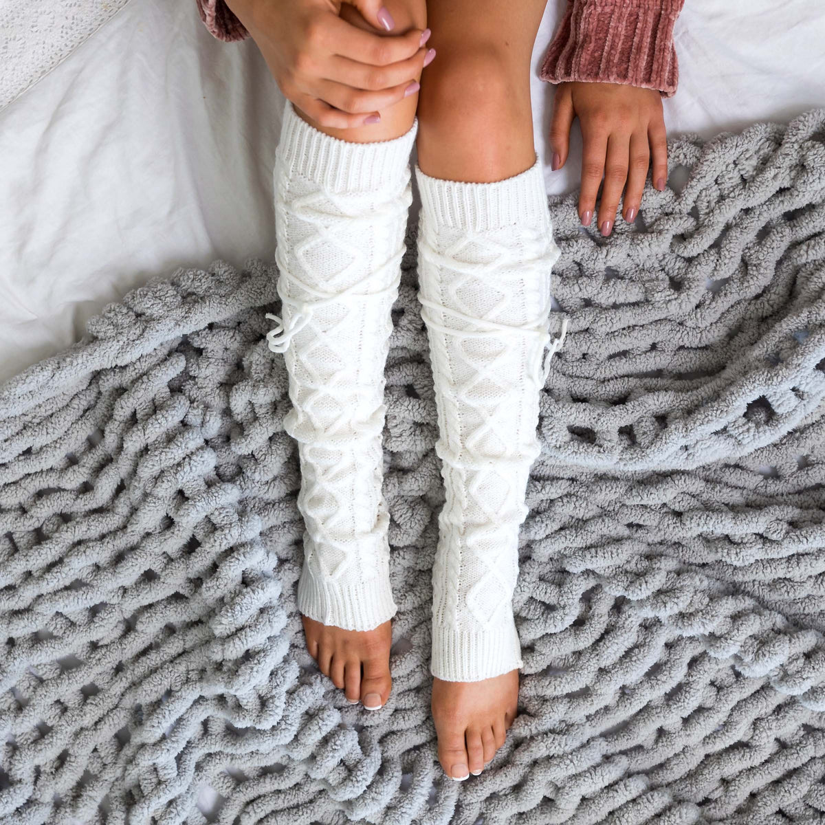Ivory cable-knit leg warmers shown from above.