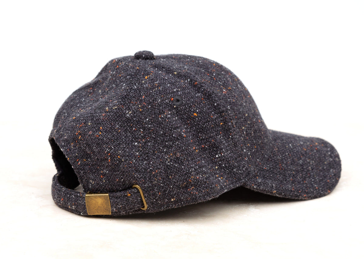 Navy tweed-style baseball cap shown from the side on a white background.