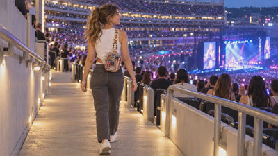 AI-assisted stadium lifestyle scene featuring a model wearing the Mocha Noelle clear sling bag. Styling props shown.