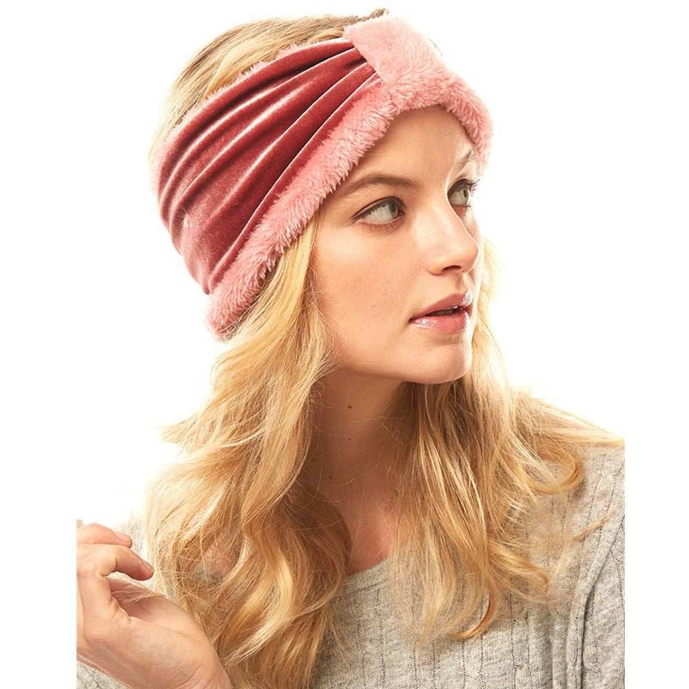 Pink velvet-look knotted ear-warmer headband with plush trim worn on a model.